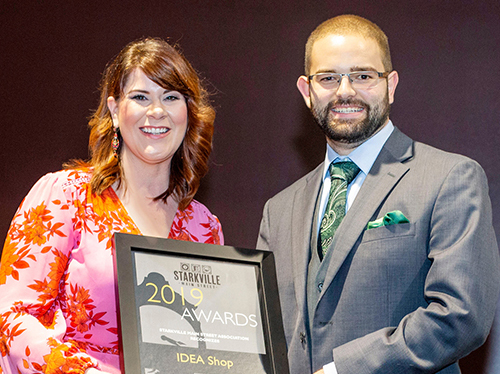 Starkville Main Street Association Chair Alaina Prentice presents an award recognizing the MSU Idea Shop as the 2019 Partner of the Year to Idea Shop Program Coordinator Michael Lane.